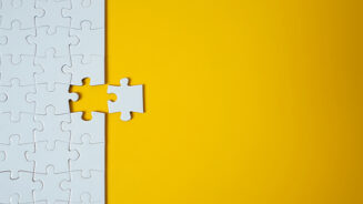 White jigsaw puzzle on yellow background. Team business success partnership or teamwork.